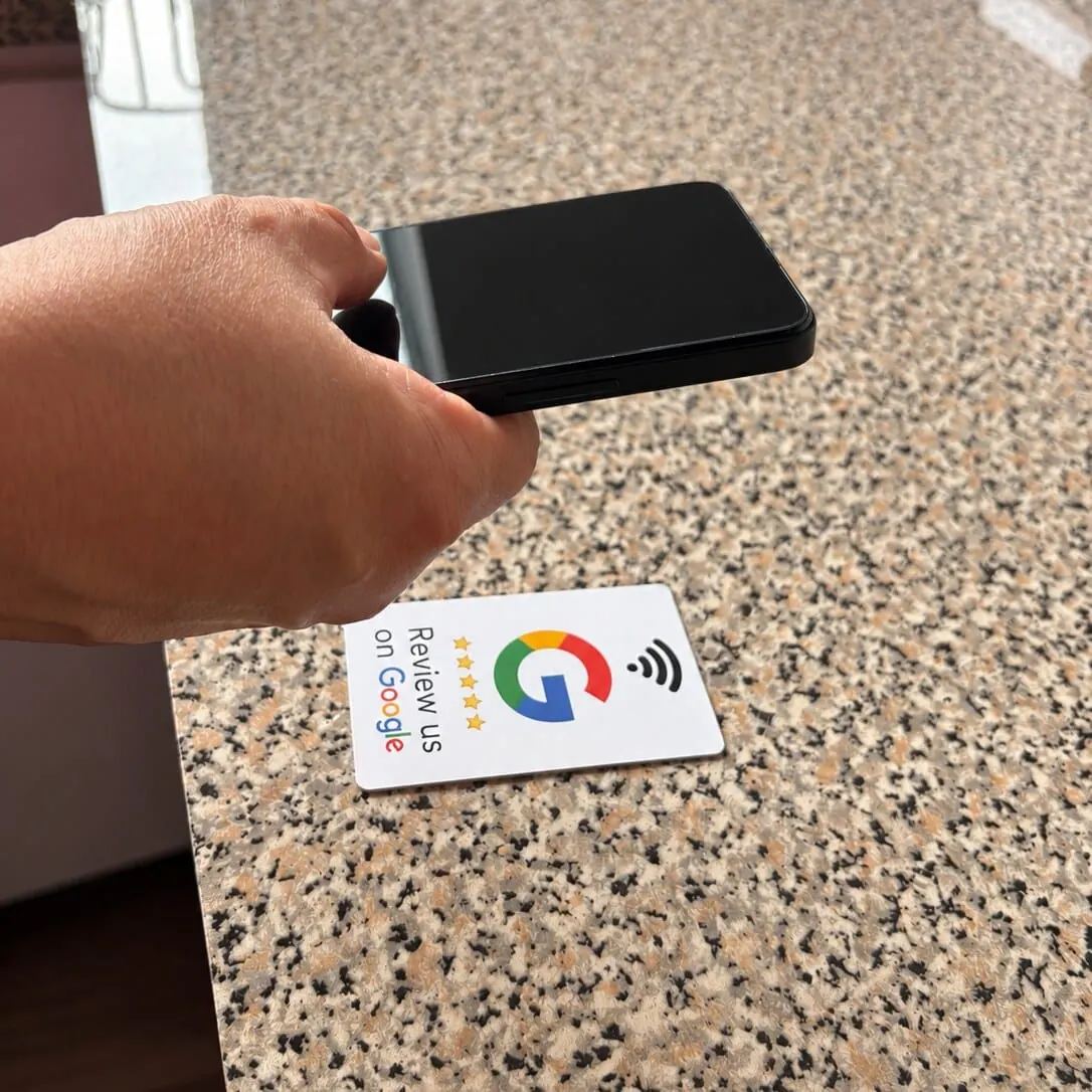 Una persona acercando su celular a una tarjeta NFC TOKIVA sobre un mesón